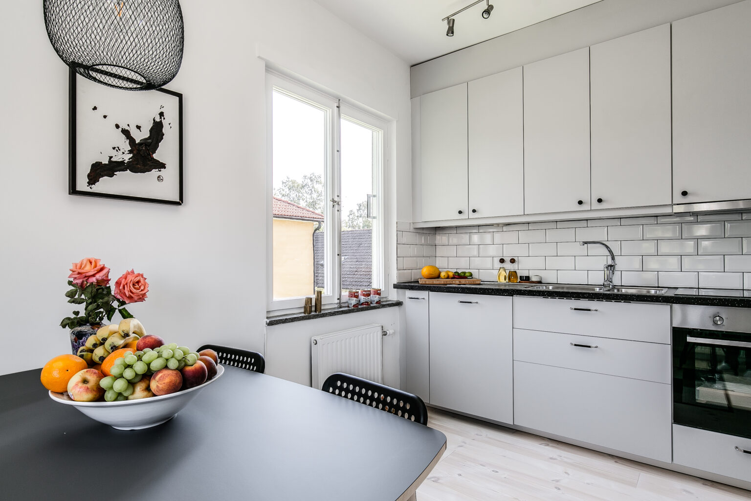 Nyinstallerat vitt kök med matbord och fruktskål i den renoverade lägenheten