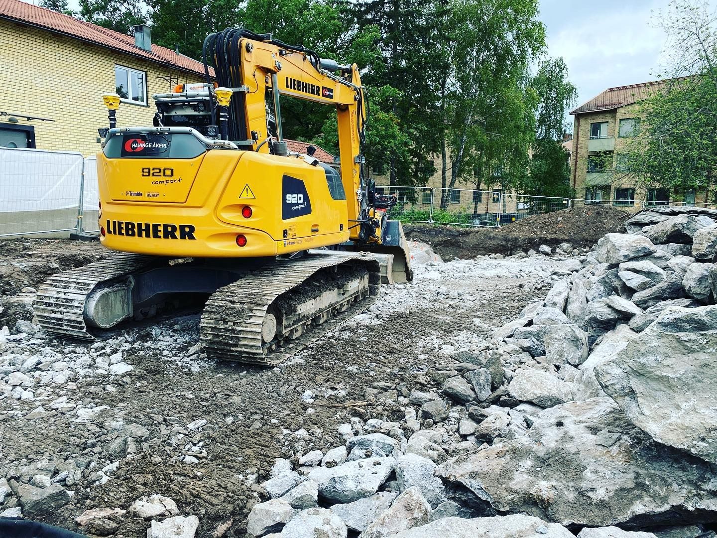 Grävmaskin på byggarbetsplats med sprängsten efter sprängning och markarbete